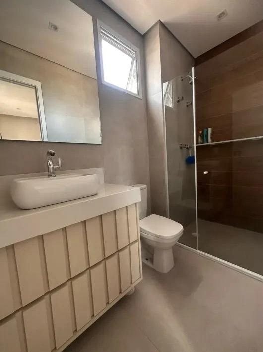 Banheiro da suíte com box de vidro e revestimento amadeirado