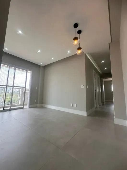 Sala do apartamento com porta para a varanda e luminária pendente