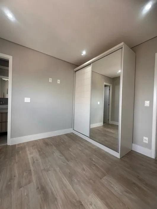 Suíte com guarda-roupa de porta espelhada e piso laminado